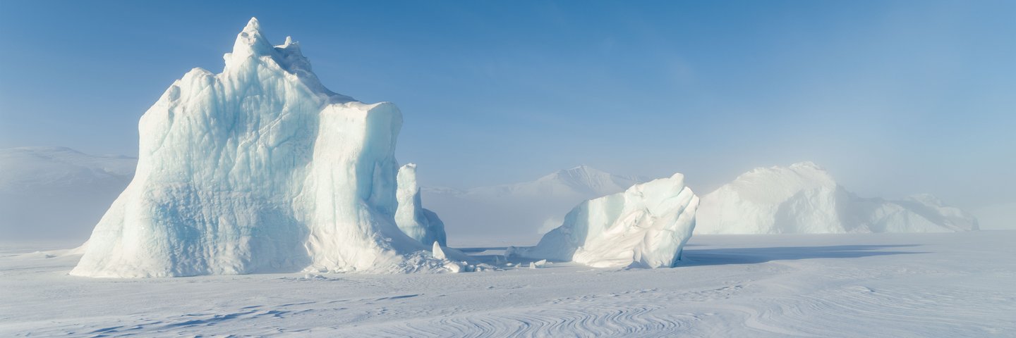 Eisberge eingefroren im Meereis des Uummannaq Fjordsystems im Winter im Nordwesten Groenlands, noerdlich des Polarkreises, Hintergrund ist vergletscherte Nuussuaq (Nugssuaq) Halbinsel_Nordwestgroenland_©_Martin_Zwick_Naturfoto